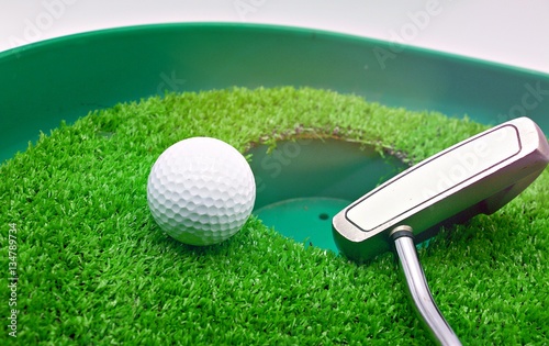 golf ball near hole with putter