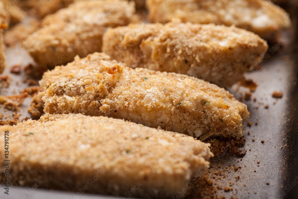 Oven Baked Parmesan Crusted Chicken Tenders on a seasoned baking stone