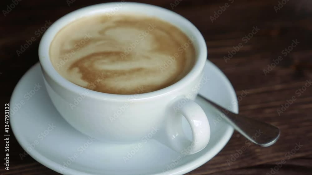 White cup with coffee, saucer and teaspoon on wooden table surface. Close-up. Panoramic view. White cup with coffee, saucer and teaspoon on wooden table surface. Close-up. Panoramic view.