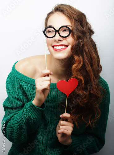 Playful young woman holding a party glasses. 