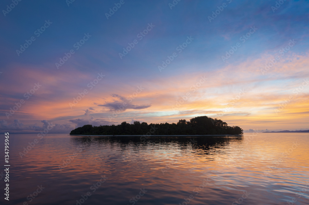 Raja Ampat Island at Sunset. There are around 1,500 uninhabited and remote islands in the Raja Ampat area of eastern Indonesia. This one is featured during a glorious sunset.