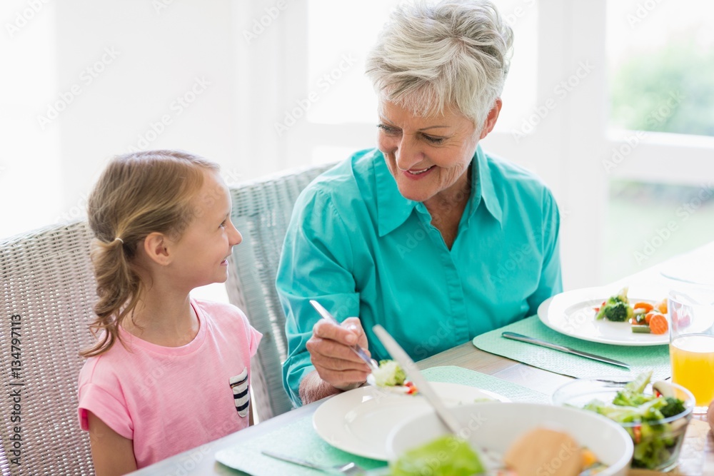 Grandmother serving a food to granddaughter