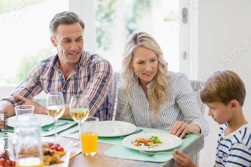 Parents interacting with son on dining table