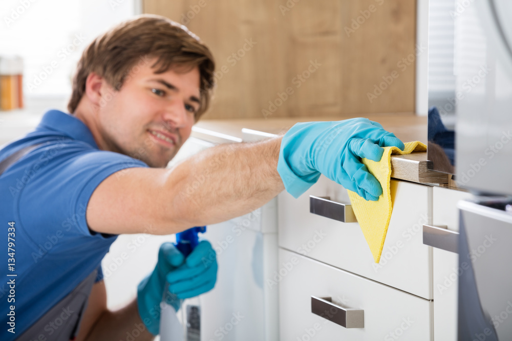 Male Worker Holding Bottle Spray And Cleaning Countertop Male Worker Holding Bottle Spray And Cleaning Countertop