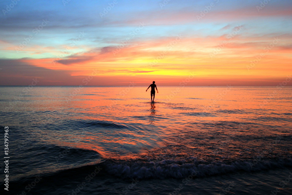 Koh Chang, Thailand. The walking man on the beach on the colorful sunset.