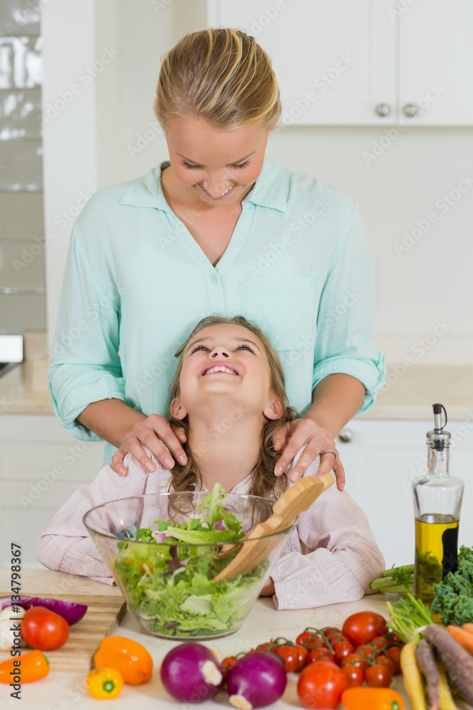 Smiling daughter interacting with mother in kitchen Smiling daughter interacting with mother in kitchen