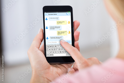 Person Sending Text Message Using Mobile Phone photo