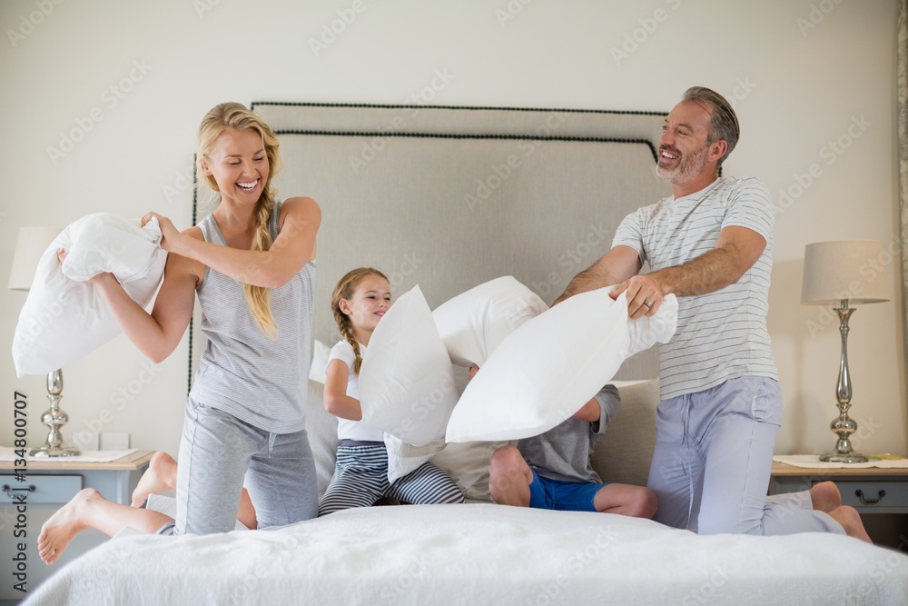 Obraz premium Cute family having a pillow fight in bedroom