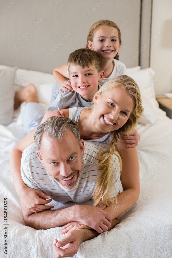 Happy family stacking on top of each other on the bed