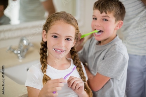 Siblings brushing teeth in bathroom