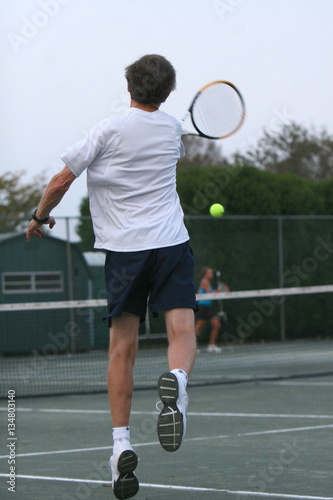 A tennis player hits a topspin forehand jumping to add power to his return of serve © Jeff