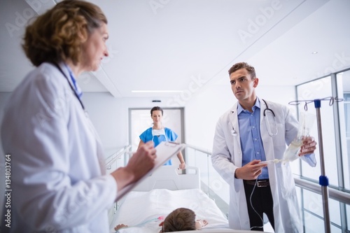 Doctor adjusting iv drip while patient lying on bed