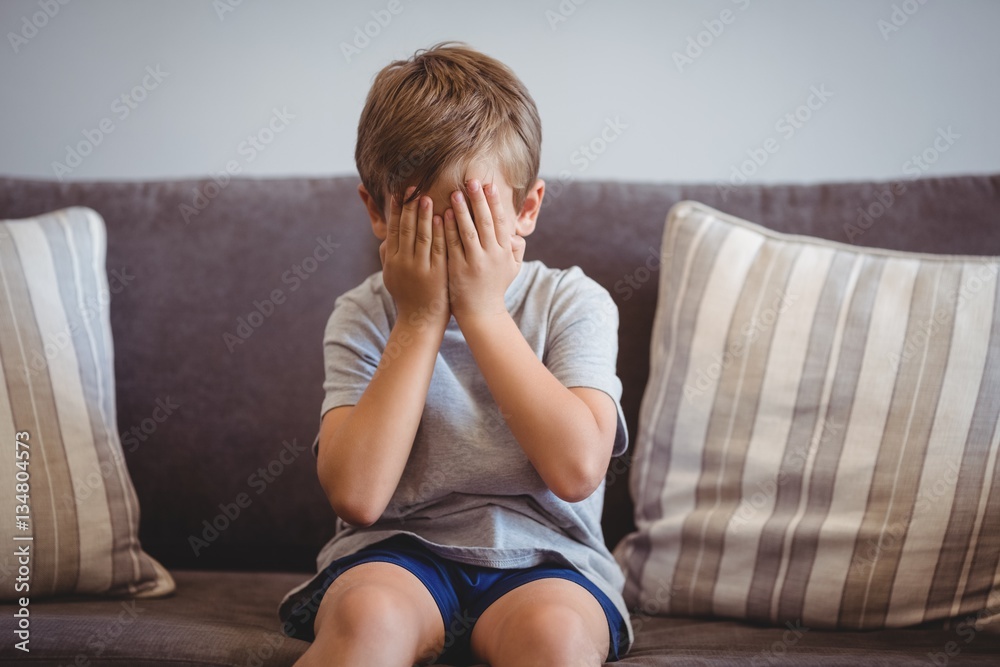 Obraz premium Upset boy sitting on sofa in corridor