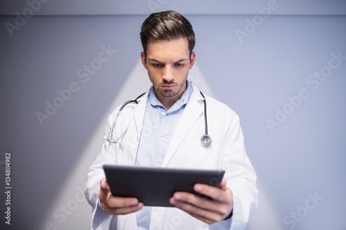 Doctor using digital tablet in corridor