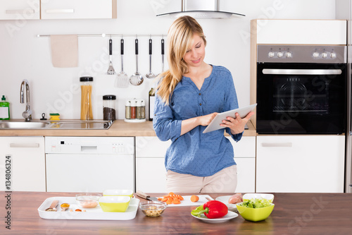 Smiling Woman Using Digital Tablet In Kitchen © Andrey Popov