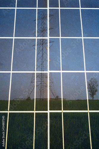 Closeup solar cell panel surface reflected transmission tower on the meadow