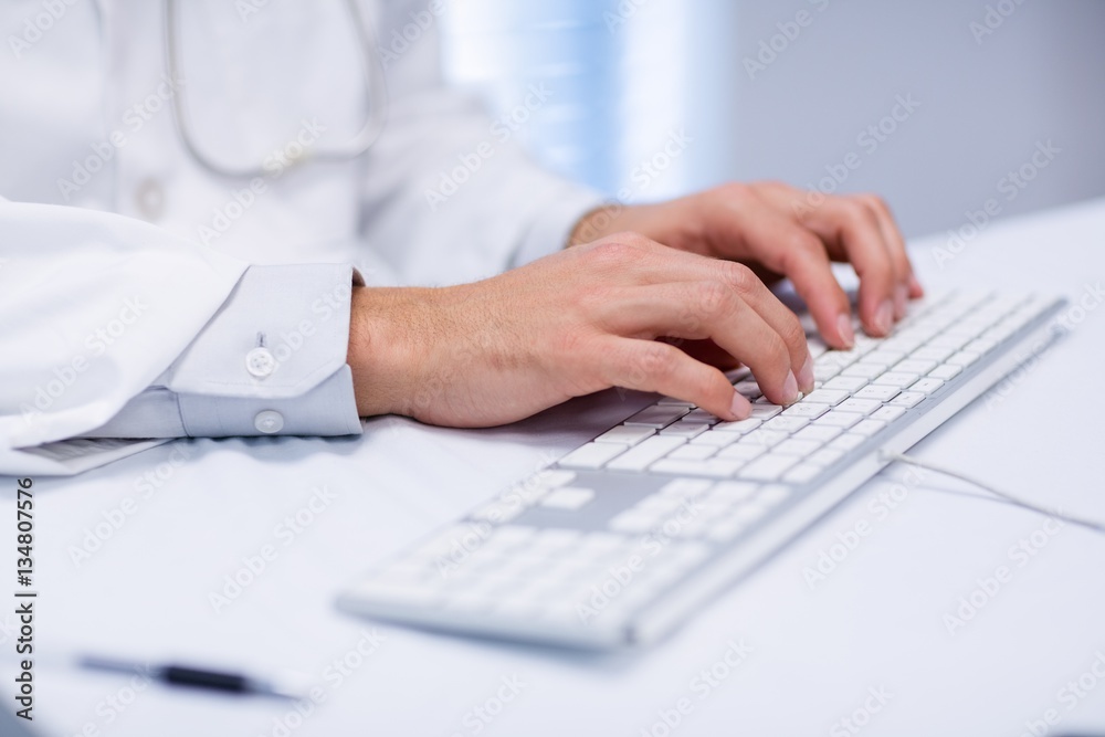 Mid section of doctor typing on keyboard Mid section of doctor typing on keyboard