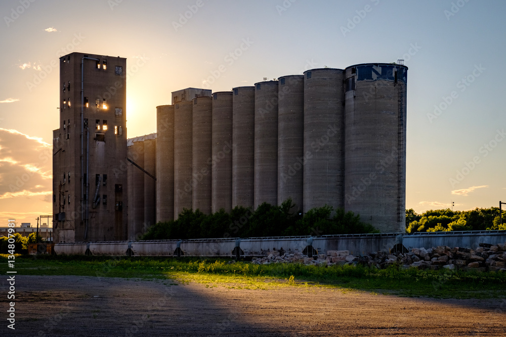 Silhouette of a grain silo at dusk backlit by the sun