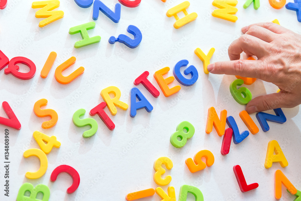 Fototapeta premium Mann bildet das Wort Strategie aus vielen bunten Buchstaben