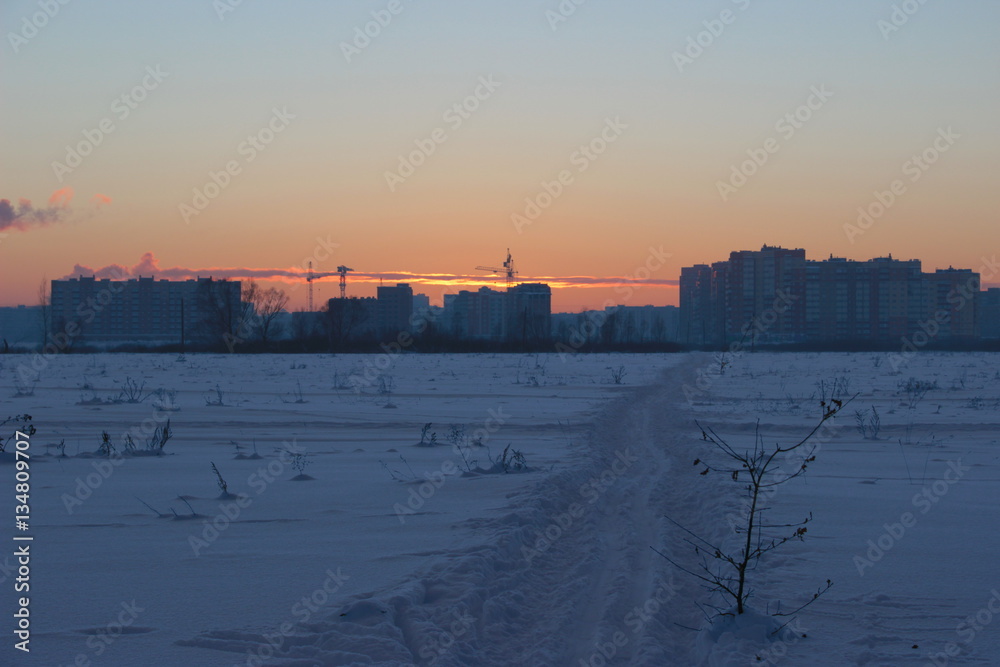 ski track towards the city, a winter evening, sunset