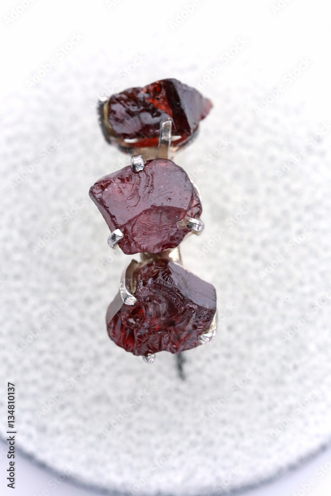 silver ring with three rough stones Garnet on a  light background 2