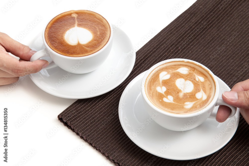 Two coffee cups of latte art heart shape place on napkin on whit
