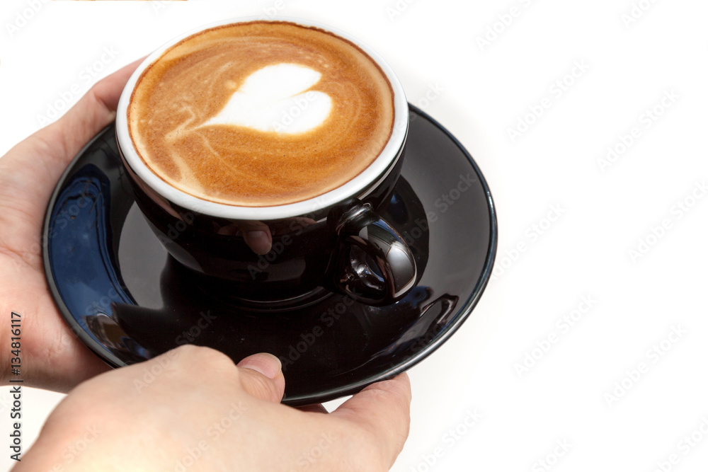 Coffee cup with heart shape latte art on top, hands serving the