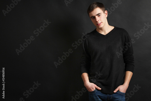 Young handsome guy posing in the studio on a black background.