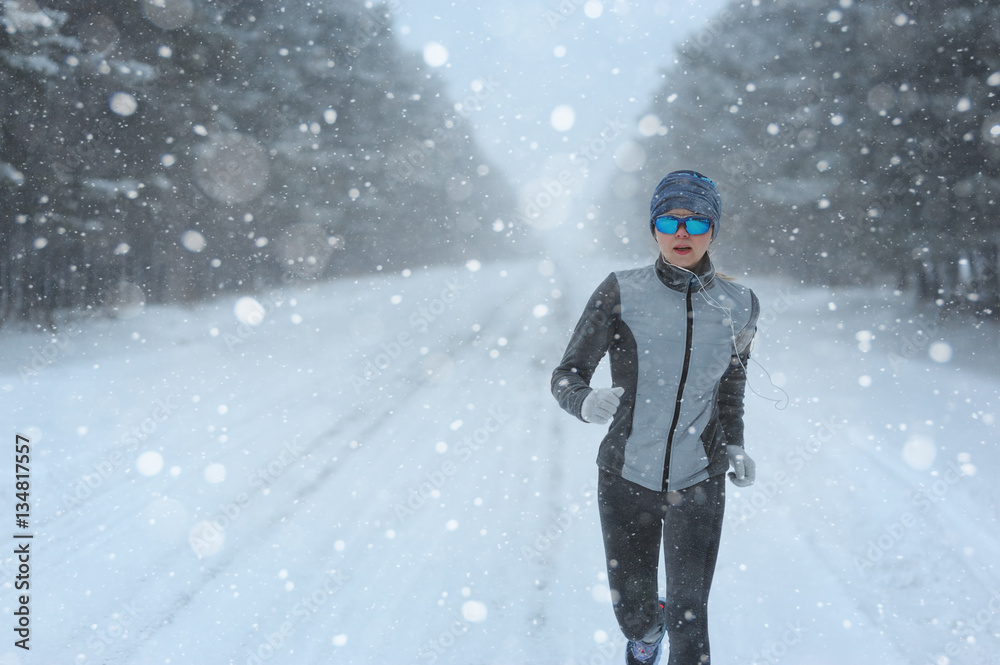 Female running sprinting up a snowy road during a winter trainin Female running sprinting up a snowy road during a winter trainin