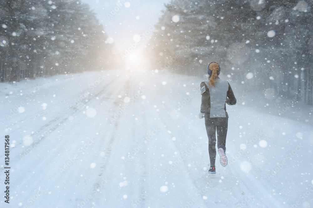 Female running sprinting up a snowy road during a winter trainin