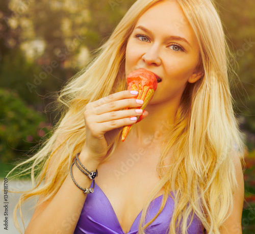 Beautiful tanned blond girl eating ice cream summer hot day. solar flare. Portrait on a street. Outdoor.