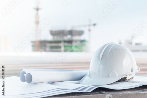 The white safety helmet and the blueprint at construction site w