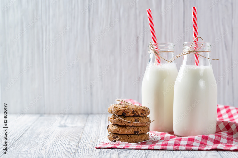 Φωτογραφία Bottles of milk with red striped straws and chocolate chip cookies on wooden bac