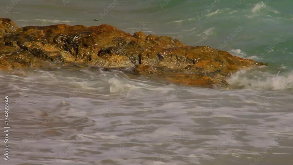 Beautiful white bubbles created on the beach by ocean waves on seashore. The ocean waves hit the rocks on the beach. Beautiful white bubbles created on the beach by ocean waves on seashore. The ocean waves hit the rocks on the beach.