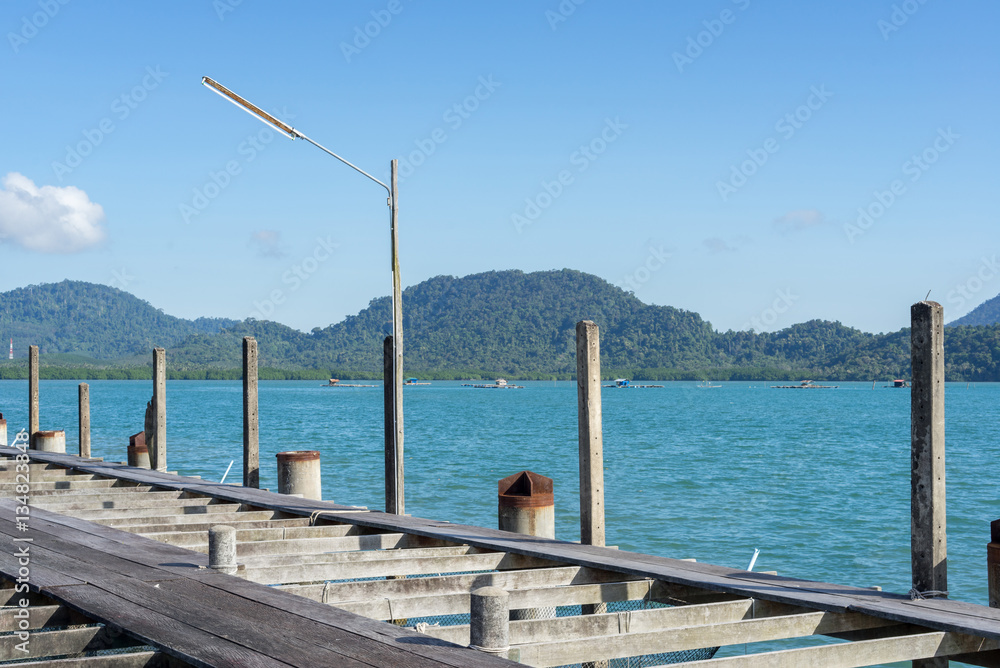 Wooden jetty in blue sea with mountain and raft houses