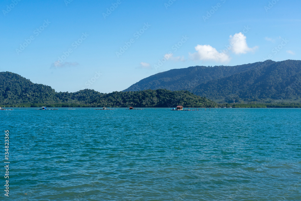 Bamboo raft houses in sea with mountain and blue sky Bamboo raft houses in sea with mountain and blue sky