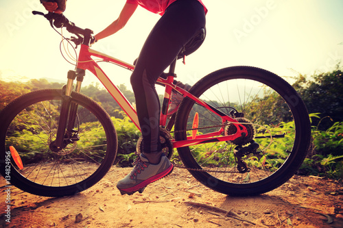 one young woman cyclist riding mountain bike on forest trail