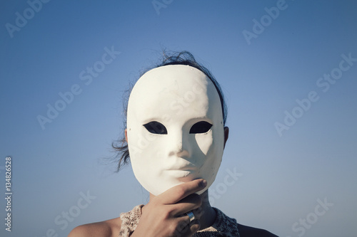 Canvas Print A woman hides her face behind a plain white mask