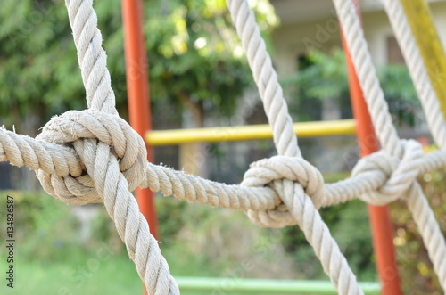 Close-up of rope knot line tied together with playground background,as a symbol for trust, teamwork or collaboration.