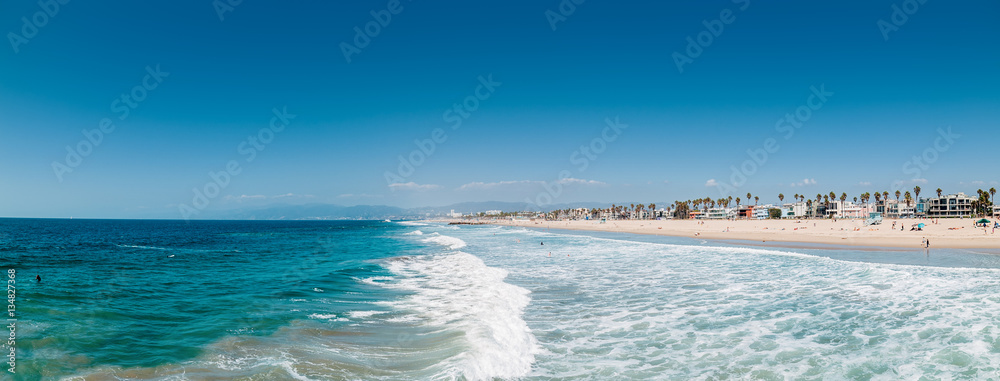 Naklejka premium Pacific ocean coastline in Los Angeles USA. People walking at the beach. Ocean waves and foam.