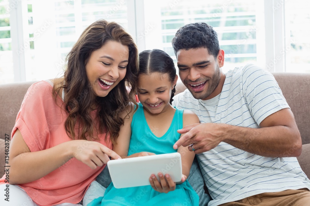 Parents and daughter using digital tablet in living room Parents and daughter using digital tablet in living room