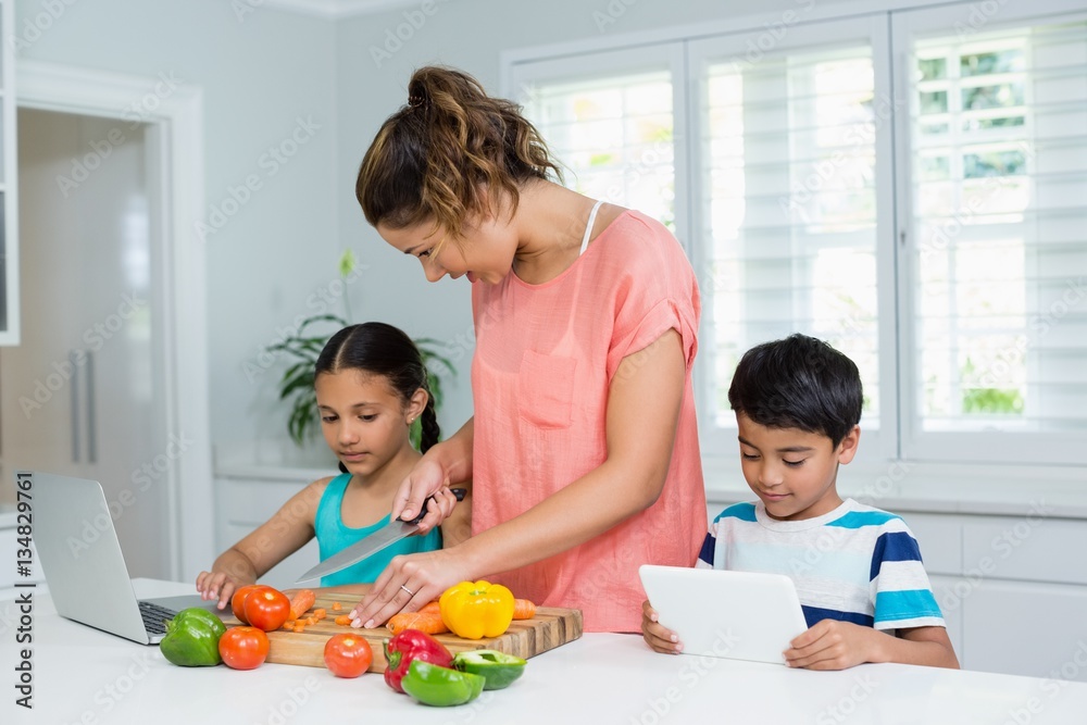 Kids using digital tablet while mother cooking Kids using digital tablet while mother cooking
