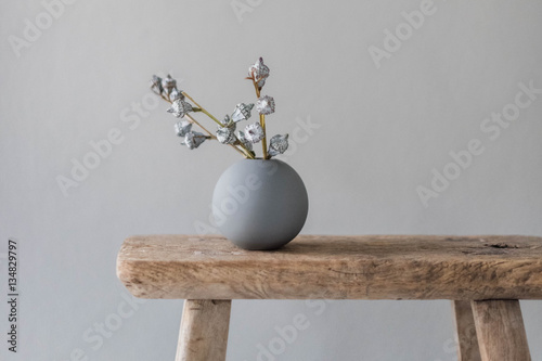 eukalyptus zweig in runder vase auf altem  holzschemel vor grauer wand photo