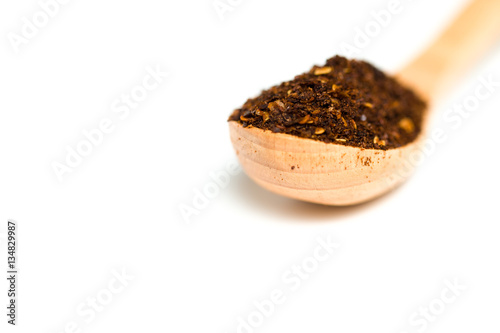 A chili flakes in a wooden spoon isolated over white background