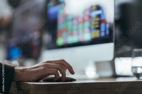 Hand of a man holding mouse on his office table.