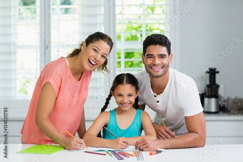 Parents and daughter drawing in kitchen at home