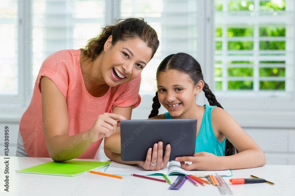 Mother and daughter using digital tablet at home