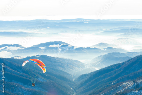 Paragliders launched into air from the very top of a snowy slope of a mountain