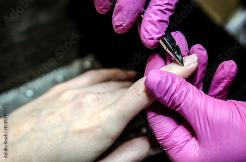 The process of removing the cuticles using tweezers for manicure.