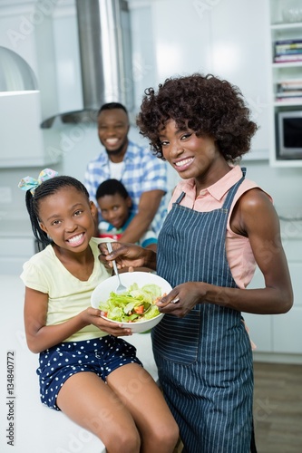 Mother and daughter preparing salad in kitchen at home